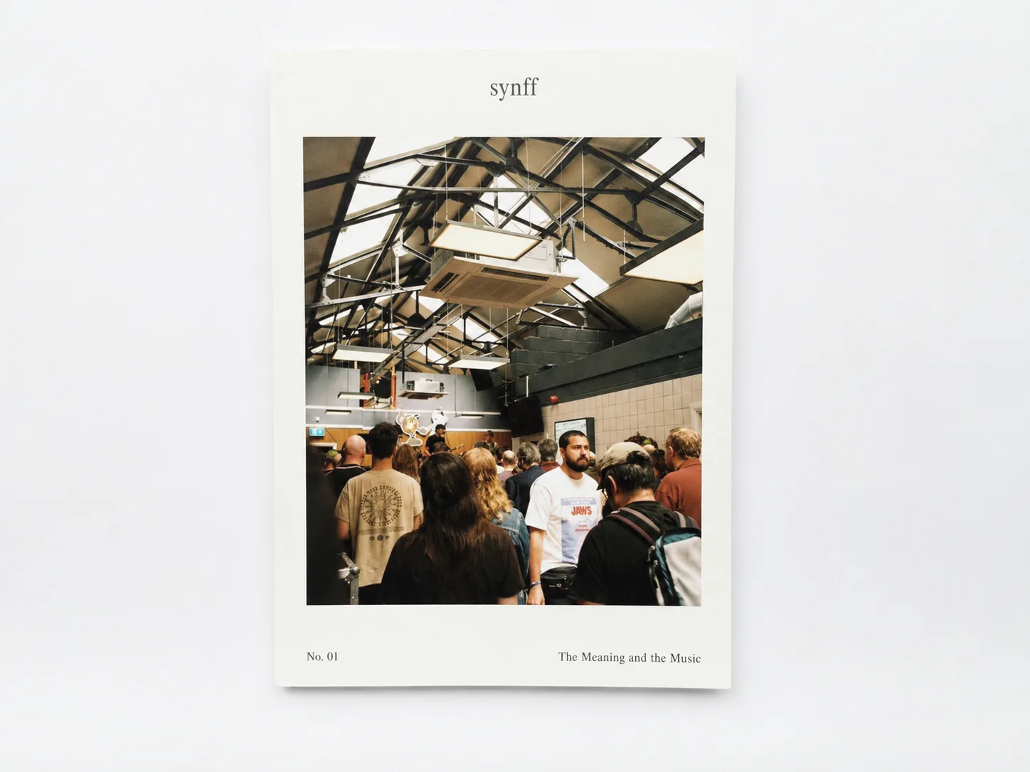 Concept of the synff launch issue cover: a crowd filing into a venue under a skylit roof